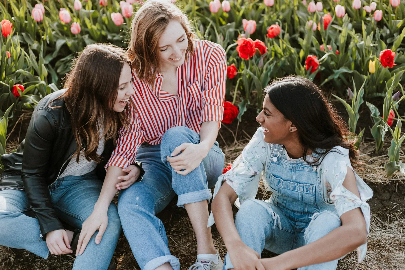 Three friends laughing in a tulip field
